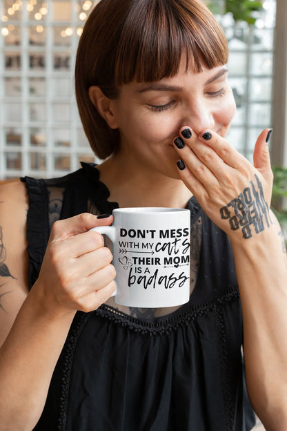 Person holding a mug with text, wearing a black sleeveless top.