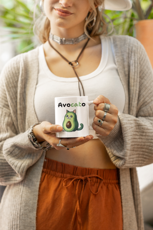 Person holding a mug with an avocado design and text, wearing a gray cardigan and orange pants.
