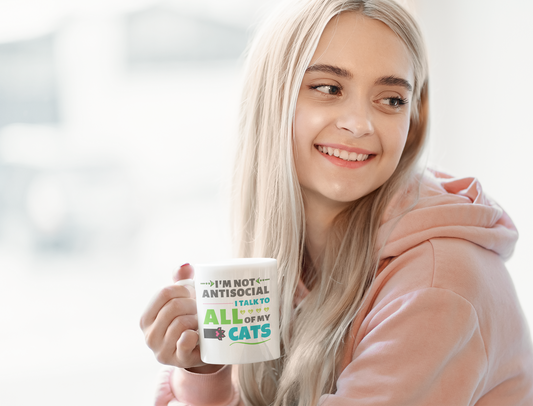 Person holding a mug with text, wearing a pink hoodie indoors.